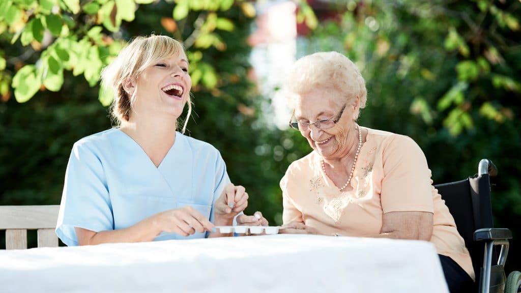 Altenpflegerin mit Seniorin am Tisch